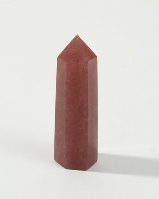 A faceted tower-shaped strawberry quartz gemstone against a white background.