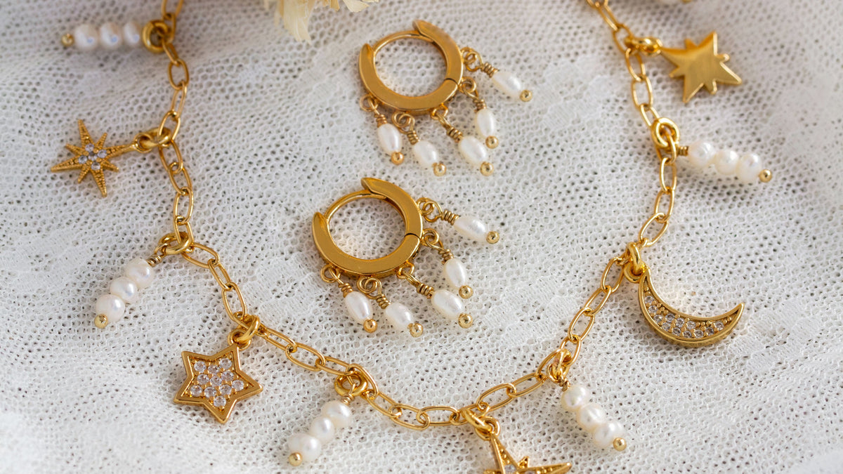 Gold jewelry set with pearls on a textured white background
