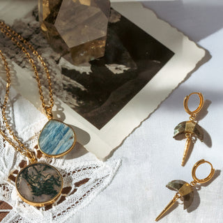 Gold gemstone jewelry with necklaces and earrings on a textured surface