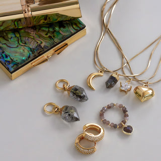 Gold jewelry with charms on a white surface