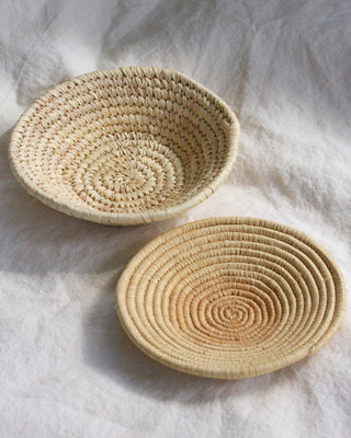 Two woven baskets on a light fabric background