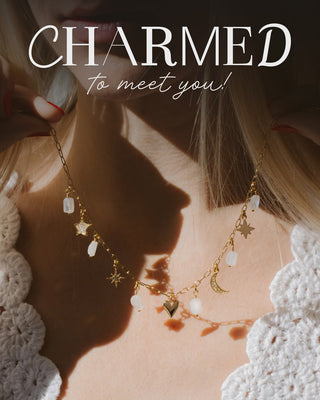 Person wearing a gold necklace with charms, text 'CHARMED to meet you!' overlayed.