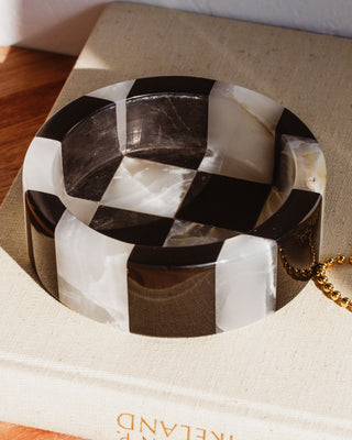 A black and white checkered pattern jewelry catchall made from genuine stone, displayed on a flat surface.