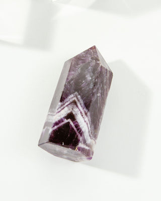A short amethyst obelisk with intricate zigzag patterns of deep purple and white.