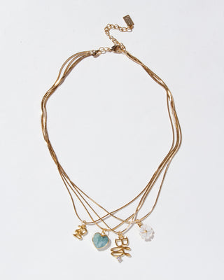 Layered gold necklaces with 2025, BFF, Aquamarine heart, and mother-of-pearl floral charms on a light white background.