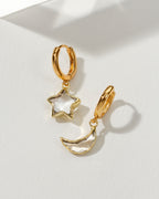 Pair of mismatched gold huggie hoop earrings with clear quartz star and moon charms
