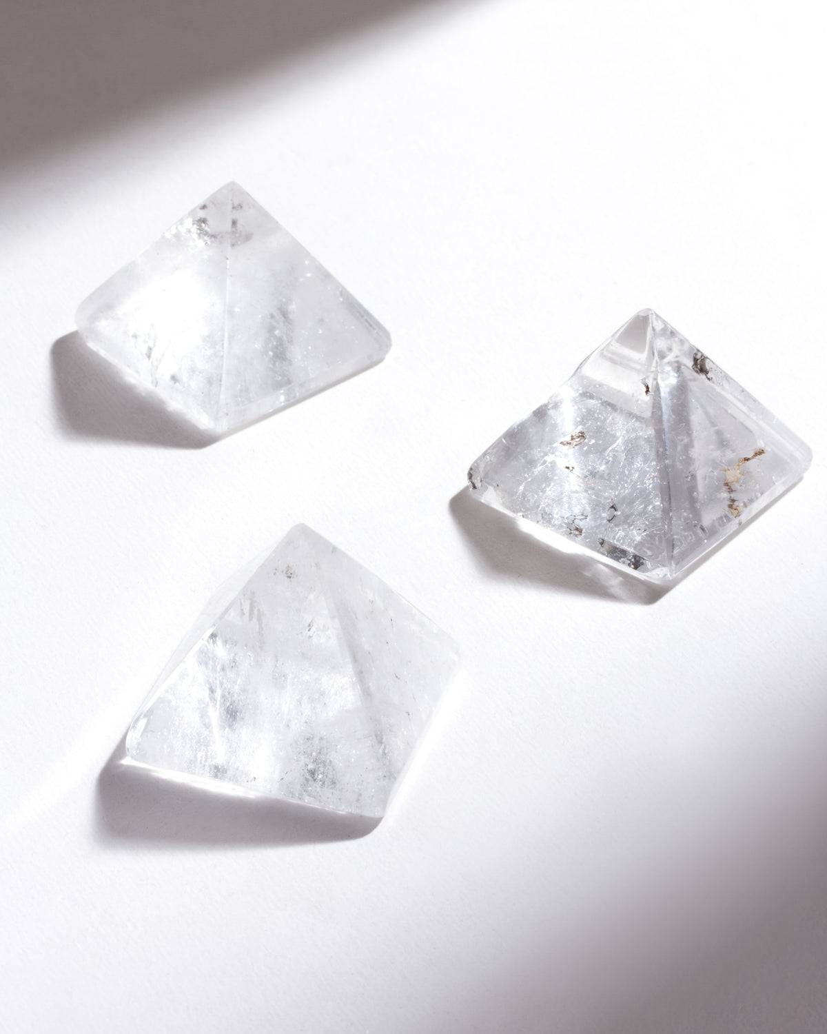 Three clear crystal pyramids on a white background.