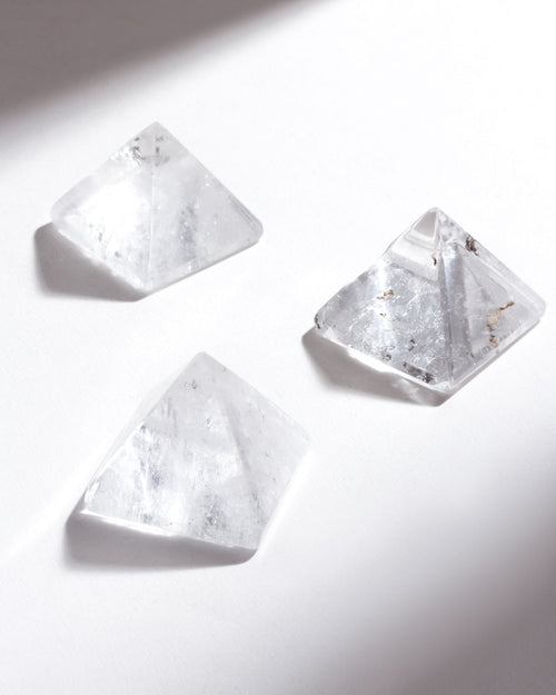 Three clear crystal pyramids on a white background.