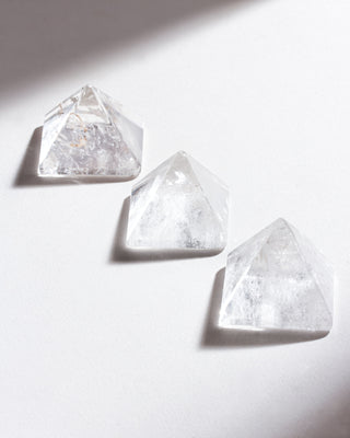Three clear quartz pyramid curios in a diagonal row against a white background.