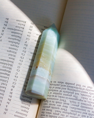 A polished amazonite gemstone tower placed on an open book, with the pages visible in the background.