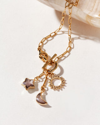 Gold necklace with coffee moonstone star, moon, and sun charm on a white background