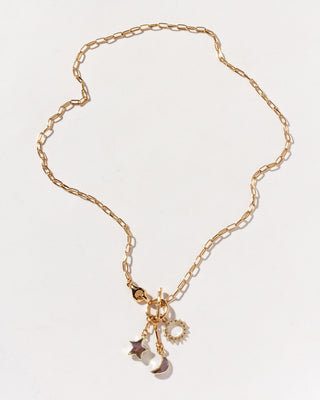 Gold necklace with star and moon charms on a light gray background