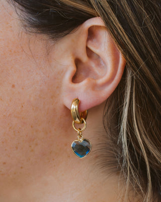 Woman wearing heart shaped labradorite gold hoop earring.