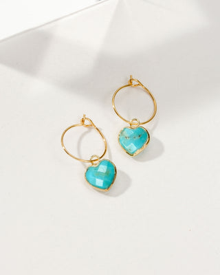 Gold hoop earrings with turquoise heart-shaped stones on a white background