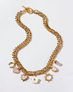 A chunky gold chain charm necklace with rose quartz, mother-of-pearl, and druzy charms