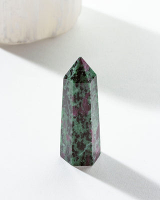 A mini Ruby Zoisite crystal tower with a green and ruby-red marbled pattern, placed on a white surface.