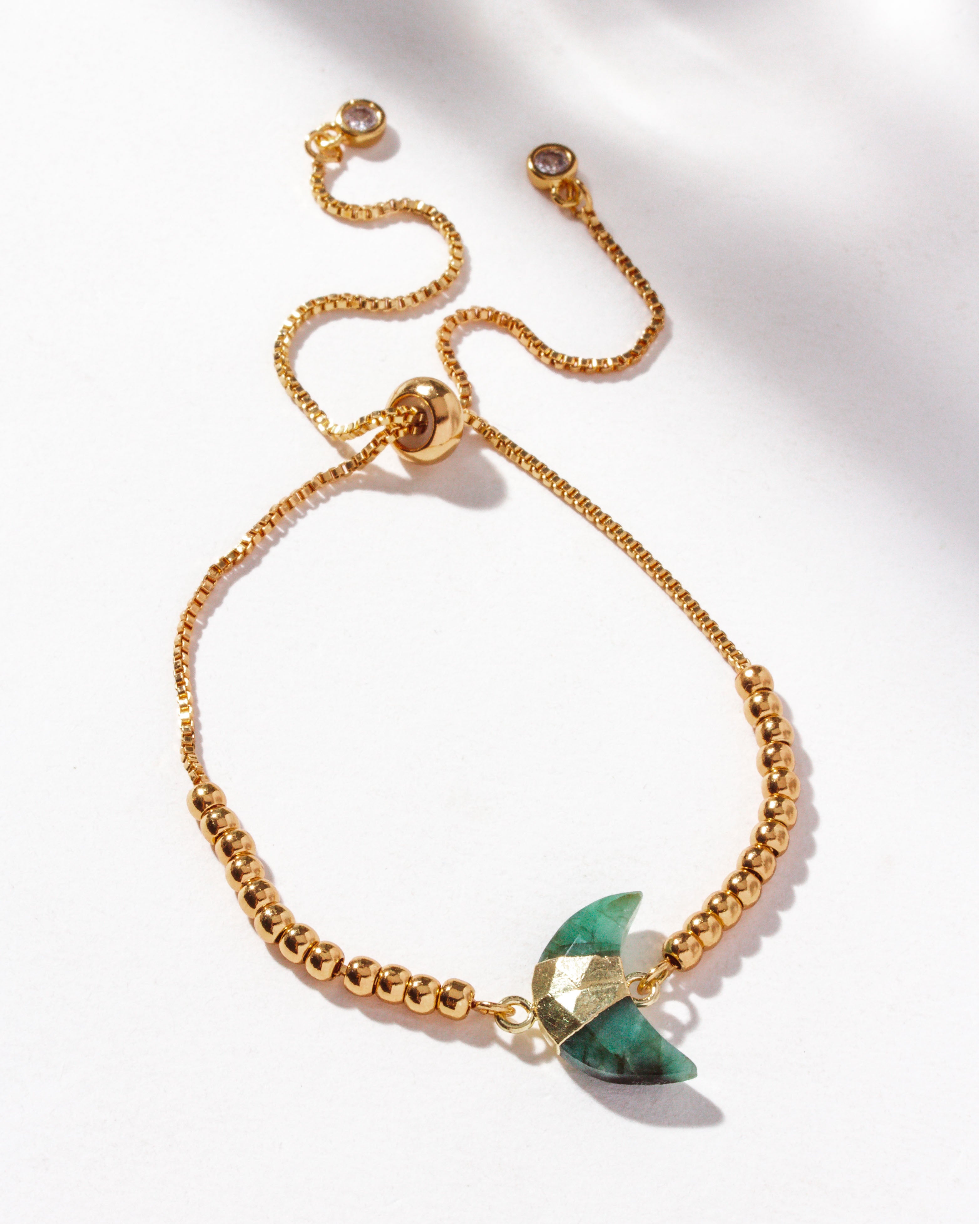 Gold adjustable bracelet with crescent emerald centerpiece, CZ crystals, and small gold beads
