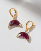 Tow Gold hoop earrings with ruby gemstone half-moon pendants on a light background