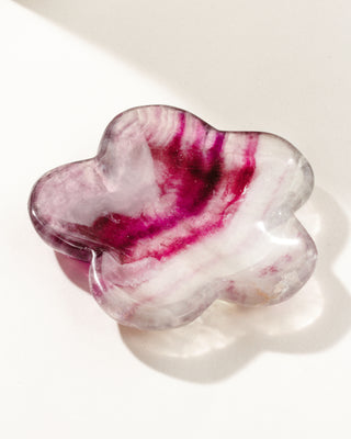 Floral shaped, reddish pink and purple and white fluorite gemstone catchall on a white background.