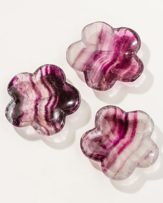 Collection of 3 floral shaped, reddish pink and purple and white fluorite gemstone catchall on a white background.
