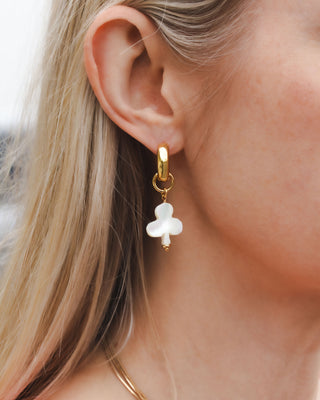 Closeup of woman wearing clubs card suite charm gold earring in mother of pearl
