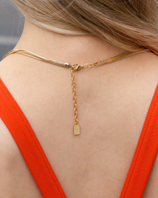 View of gold necklace clasp on woman's neck and red top.