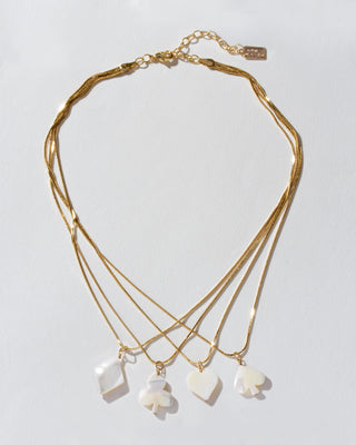 Gold layering necklace with four overlapping chains each with diamond, club, heart, and spade shaped mother of pearl card suite charm.