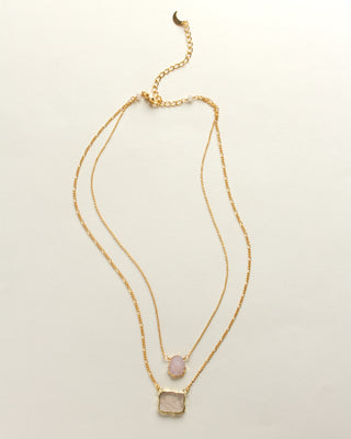 Complete image of layered necklace with a gold chain and pink Druzy and rose quartz pendants displayed on a white surface.