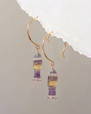 Gold earrings with multicolored gemstones on a gray background