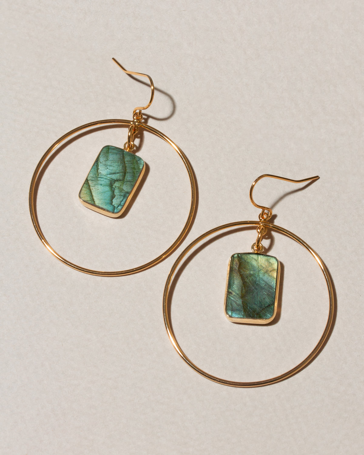 A pair of gold hoop dangle earrings with rectangular green labradorite stone charms.