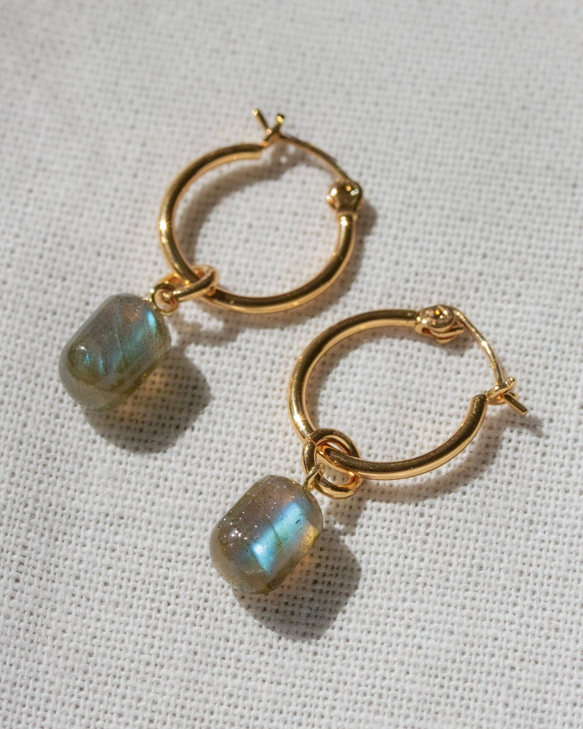 Gold Pill Drop Hoop Earrings with Labradorite gemstones next to a chess piece.