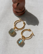 Gold Pill Drop Hoop Earrings with Labradorite gemstones next to a chess piece.
