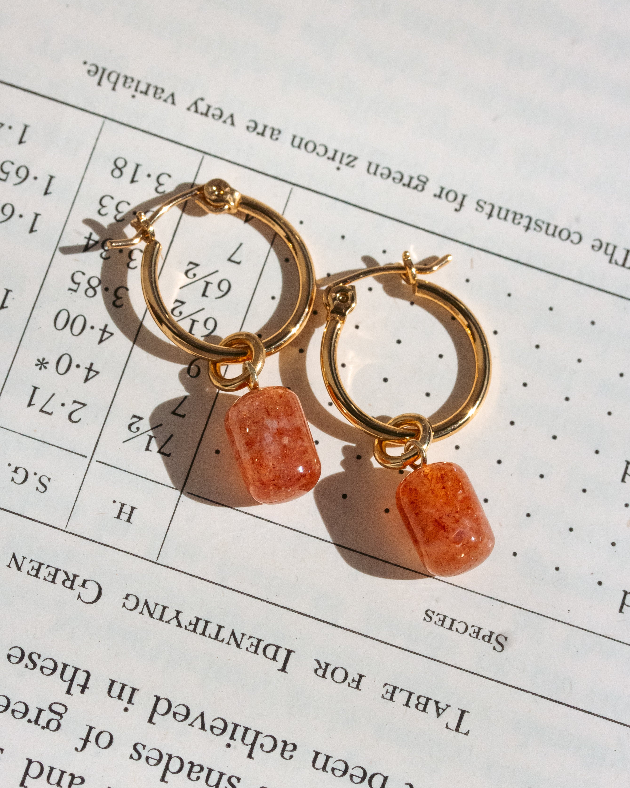 Gold hoop earrings with pill-shaped Sunstone gemstones.