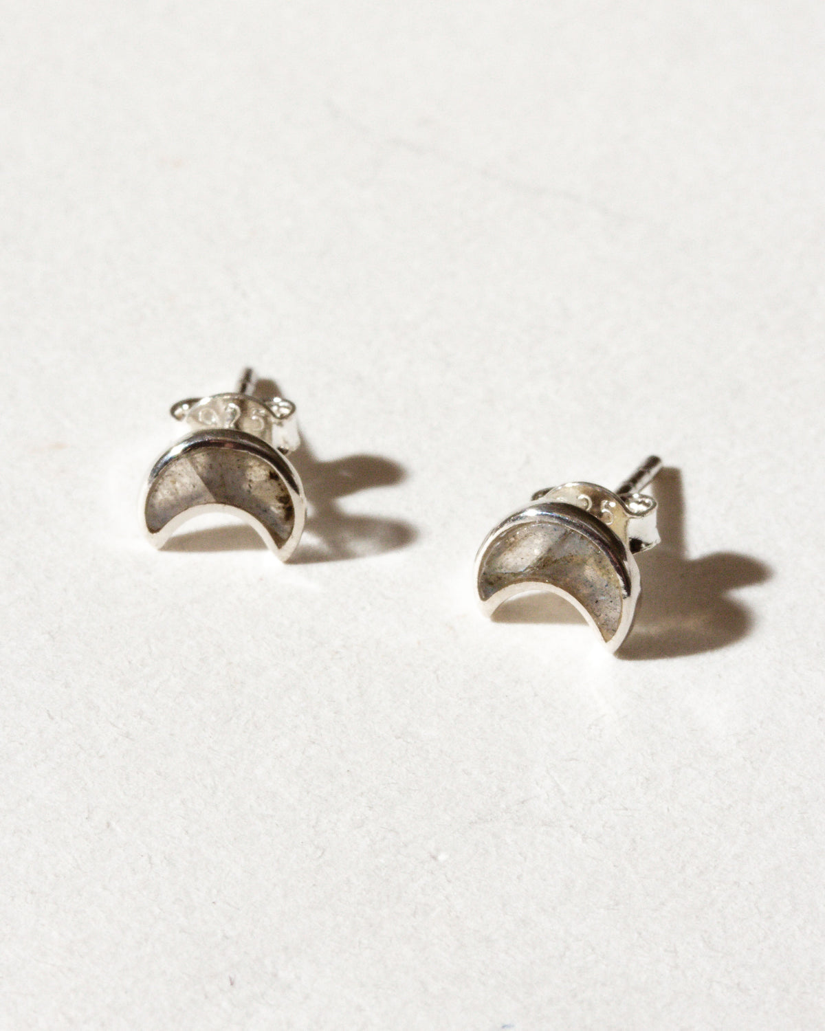 Pair of sterling silver post earrings with a crescent shape, with bezel-set labradorite stones.
