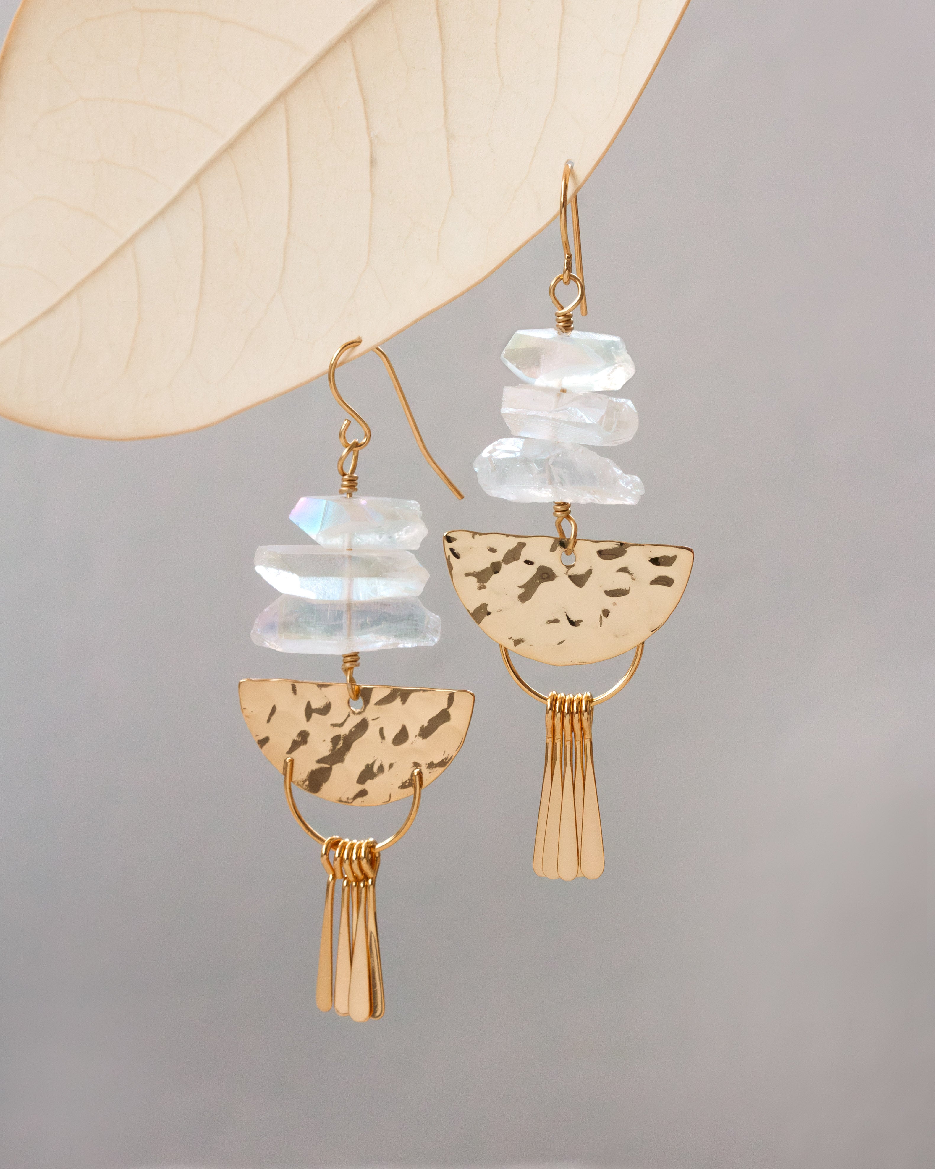 Gold and clear quartz fish hook fringe statement  earrings on a grey background