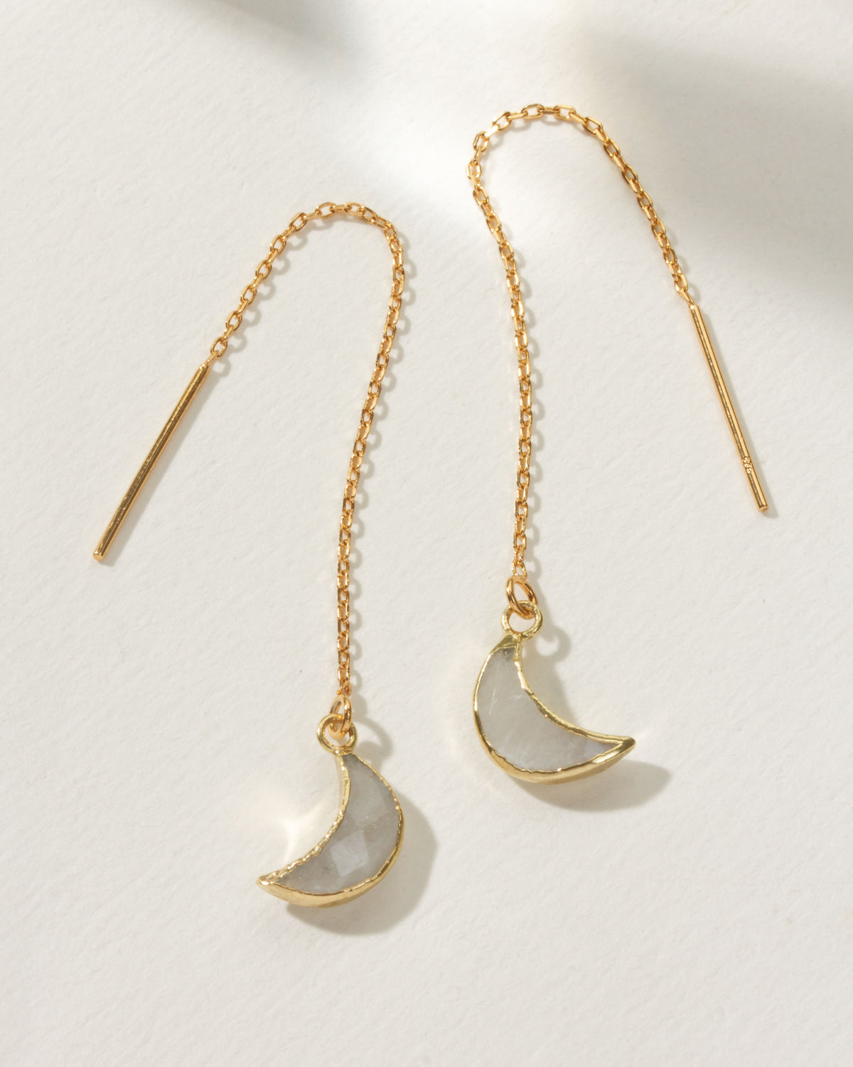 Gold threader earrings with moonstone crescent pendants.
