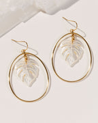14 Karat Gold-plated hoop earrings with mother of pearl leaf-shaped cutouts on a white table