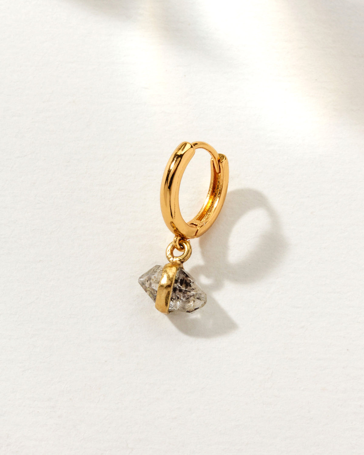 Gold hoop earring featuring a clear Herkimer Diamond quartz stone with gold band detail.