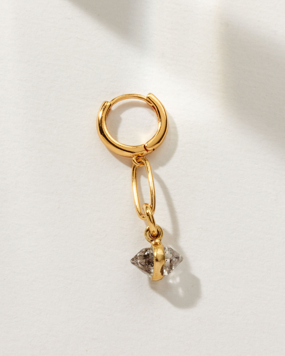 Gold hoop earring with a linked Herkimer Quartz stone.