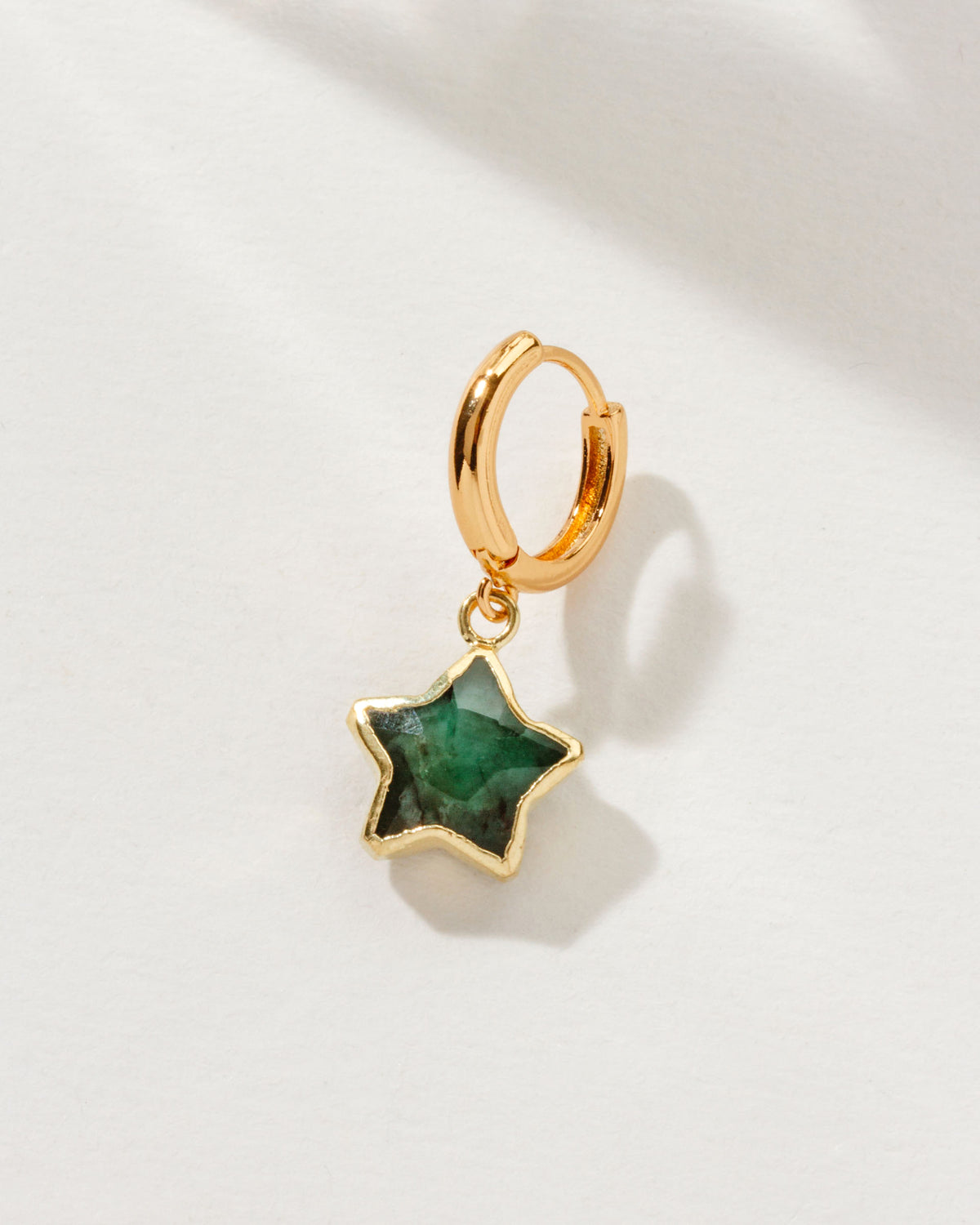 Seastar Solo Hoop Earring with a green emerald gemstone star and gold huggie hoop.