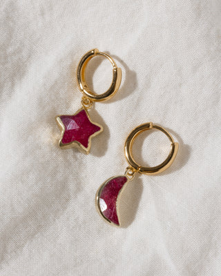 Gold huggie hoop earring with mismatch star and moon charms in ruby red gemstone.
