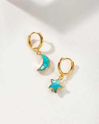 A pair of gold hoop earrings, one with a crescent moon and the other with a star, both featuring a bright turquoise blue center.