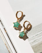 A pair of gold hoop earrings with dangling star-shaped amazonite stone charms.