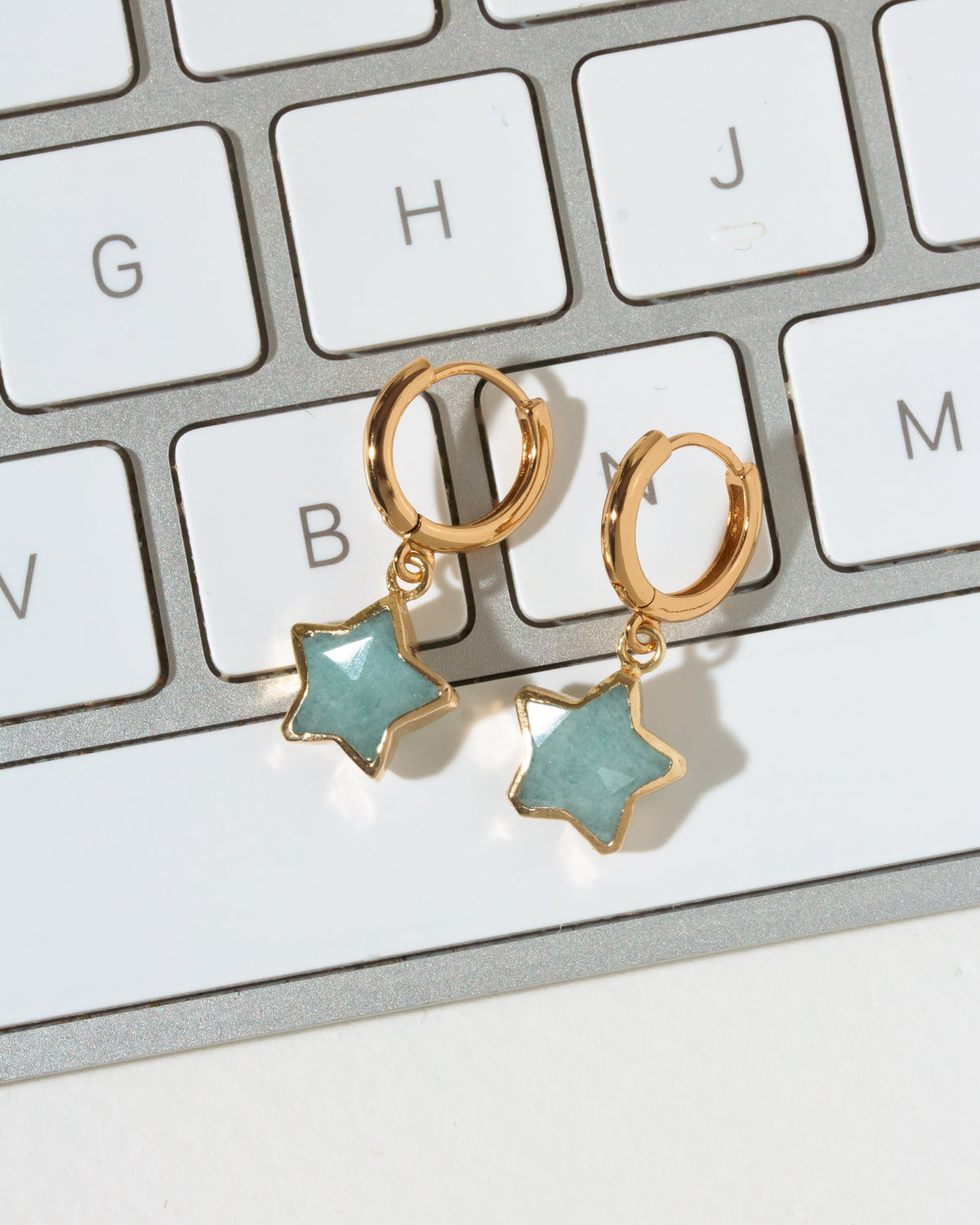 Gold hoop earrings with star-shaped light blue aquamarine stone charms.
