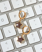 A pair of gold hoop earrings with dangling star-shaped coffee moonstone charms.