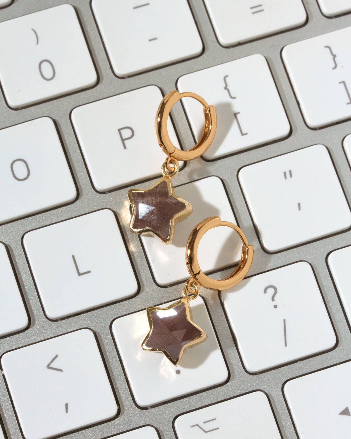 A pair of gold hoop earrings with dangling star-shaped coffee moonstone charms.