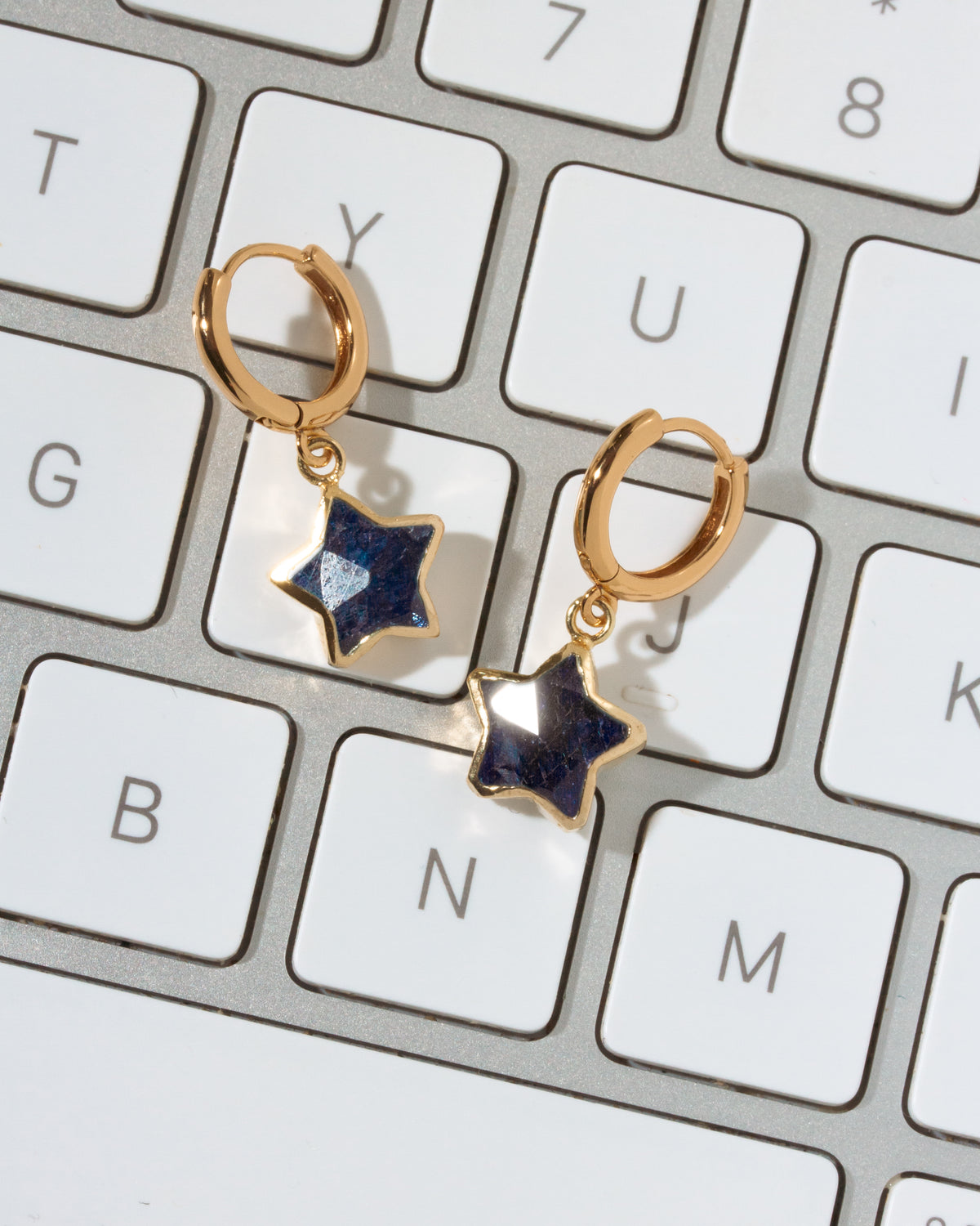 A pair of gold hoop earrings with sapphire dangling star charms.