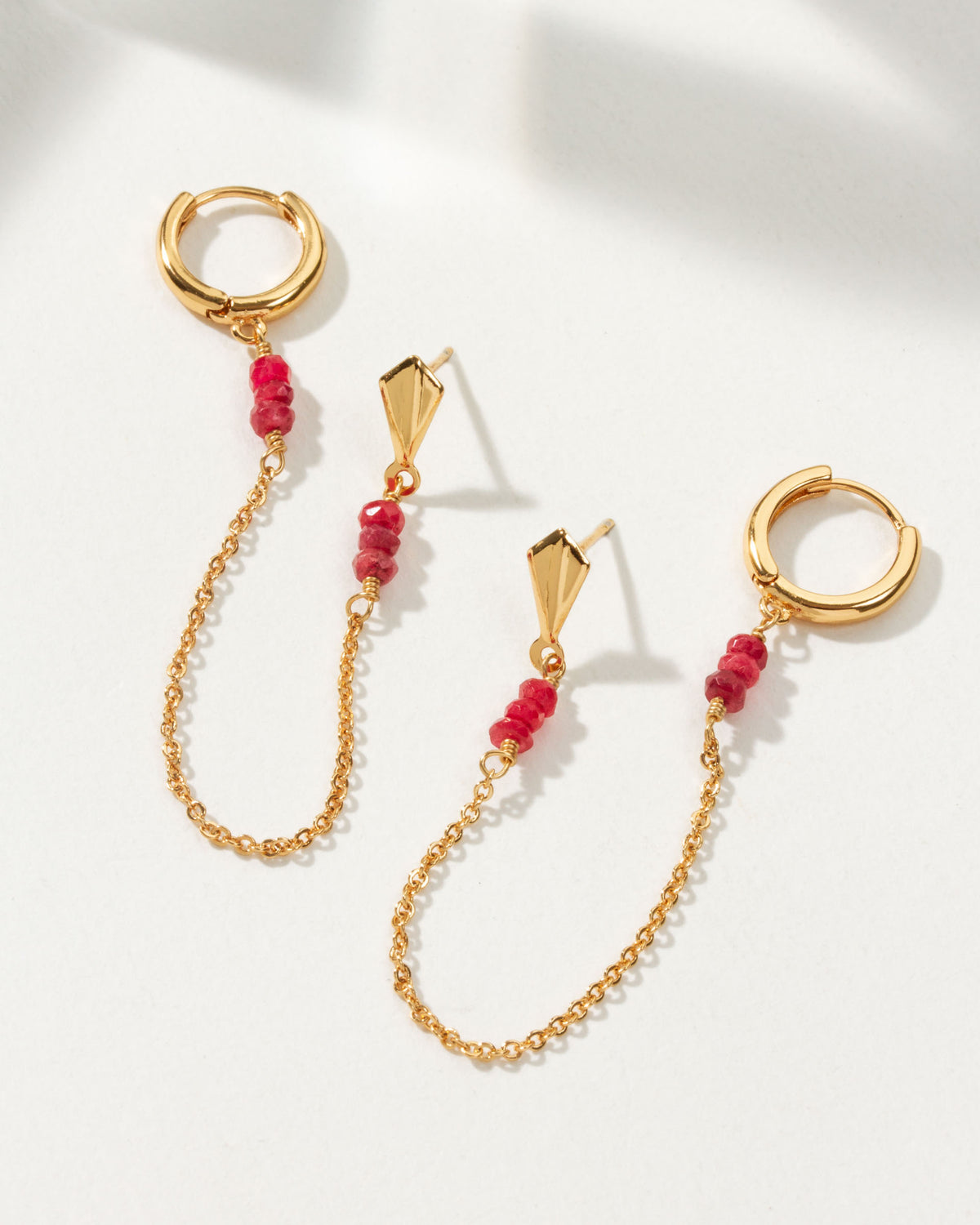 Cascades Double Pierced Hoop Earring with a gold chain and ruby gemstone accent.