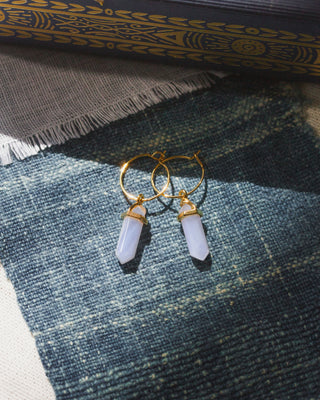 Gold hoop earrings with Blue Lace Agate pendants on a blue fabric background