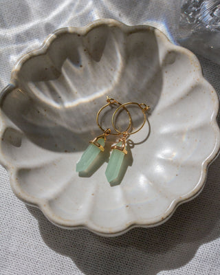 Gold hoop earrings with Green Aventurine gemstones on a ceramic dish.